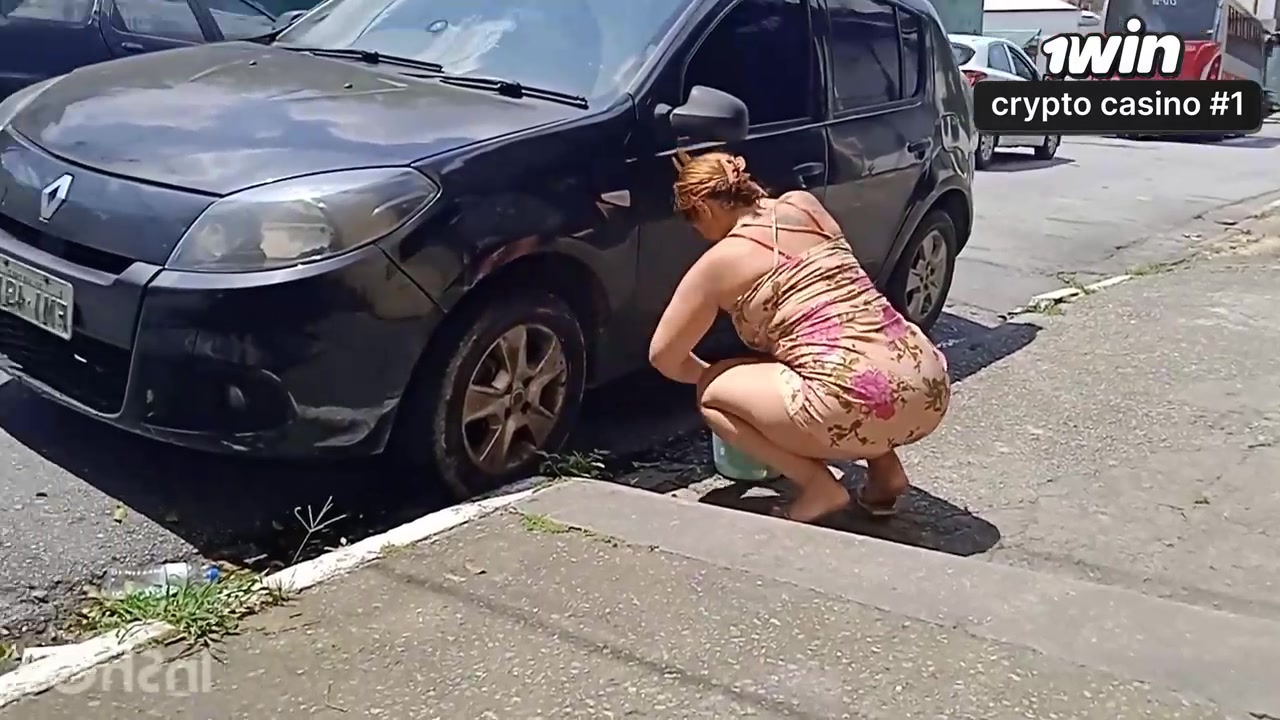 Uma mulher atraente lava o carro se exibindo na rua em cenas explícitas.